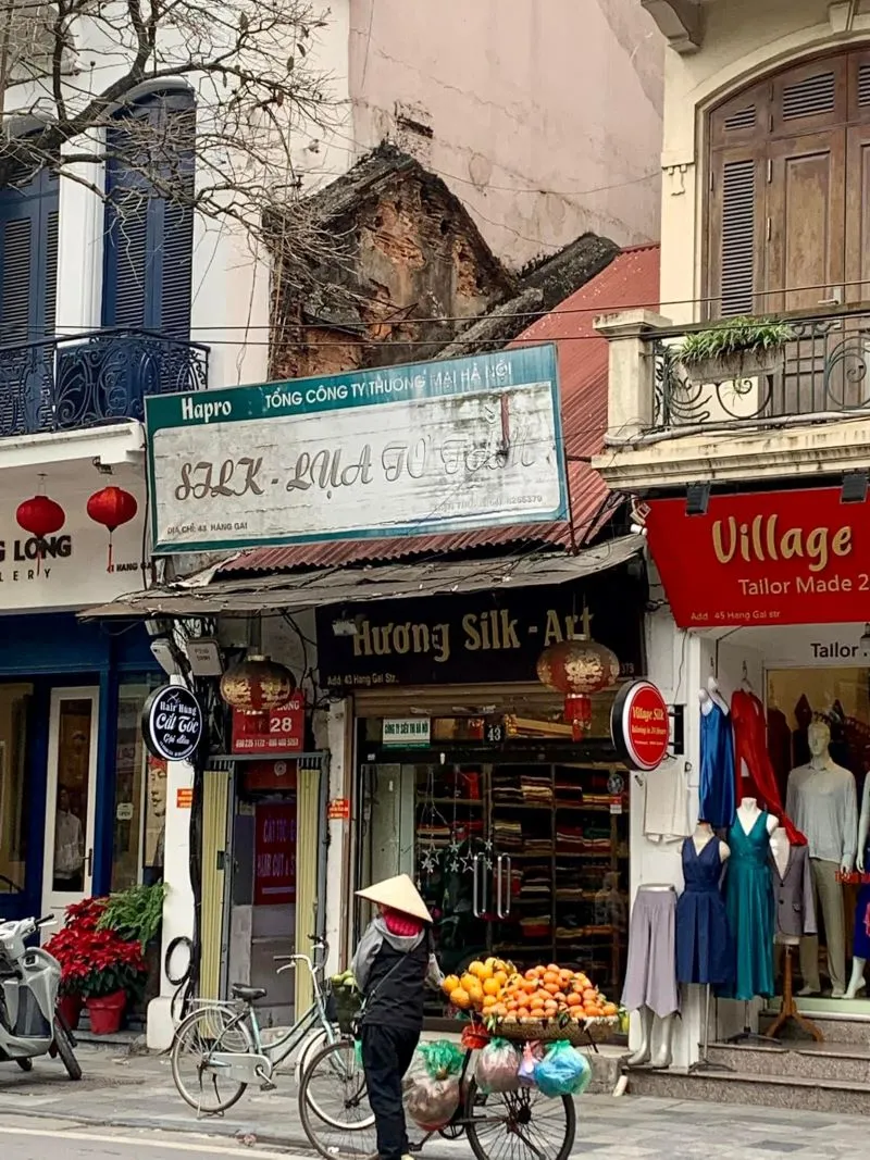 A vibrant street view of silk shops with colorful fabric rolls and custom-tailored dresses - Photo Source: Fanpage Phố Hàng Gai