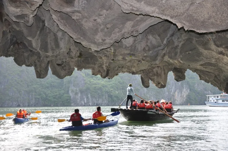 A narrow water tunnel only accessible by kayak or bamboo boat leads to a tranquil, emerald lagoon surrounded by limestone cliffs - Photo Source: Báo Quảng Ninh