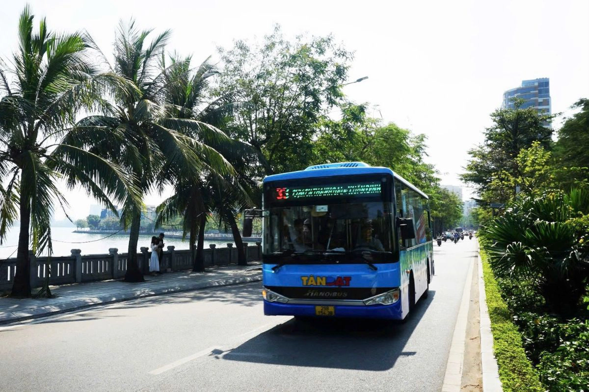 A local public bus moving smoothly along the scenic tree-lined roads bordering the water