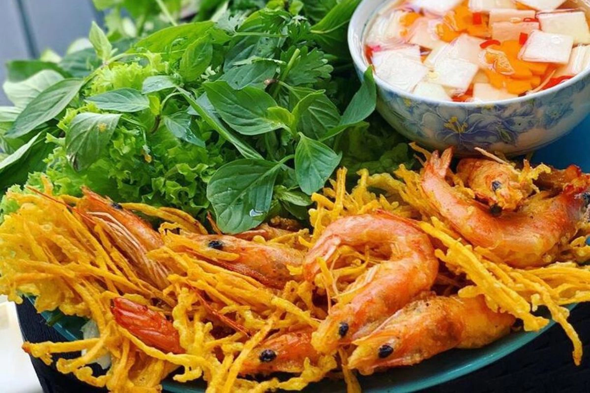 A plate of crispy sweet potato and shrimp cakes served with fresh herbs and dipping sauce