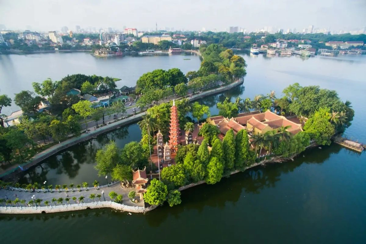 A view of the tall red stupa at Tran Quoc Pagoda surrounded by the calm waters of West Lake