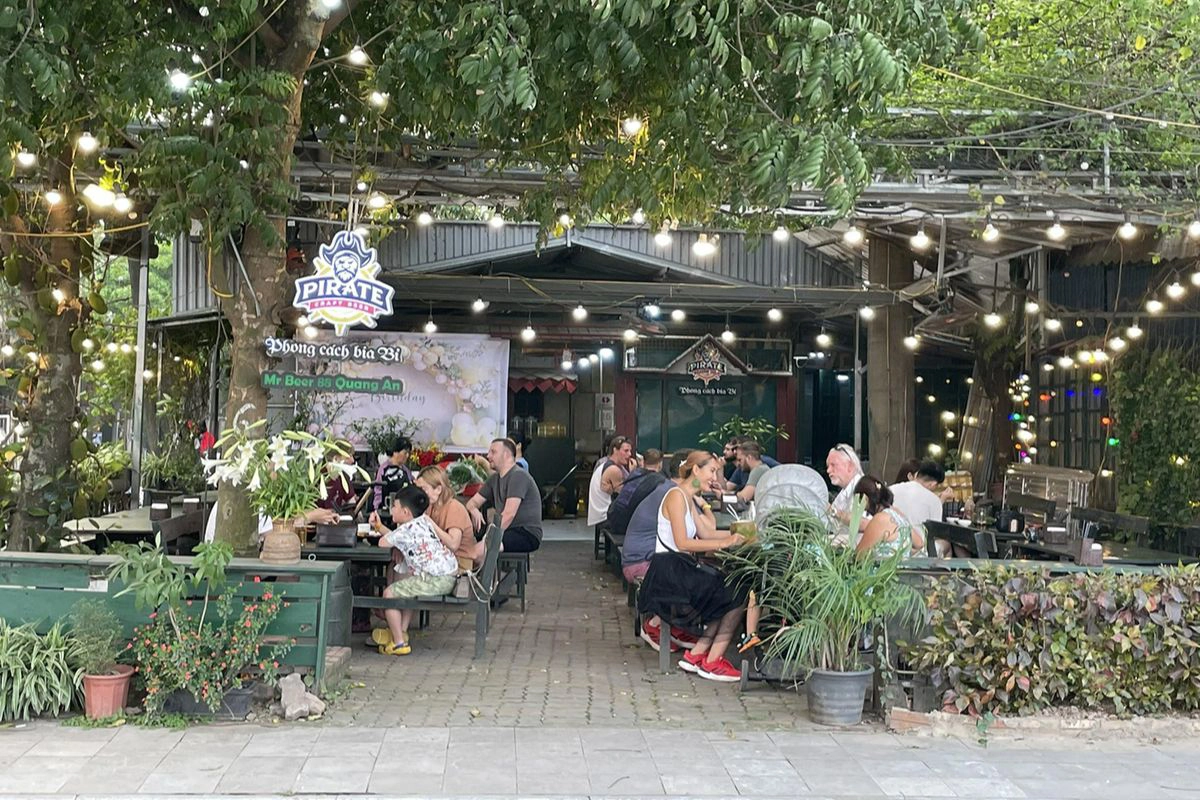 Travelers and locals enjoying craft beer and casual conversation at a venue in the Quang An area