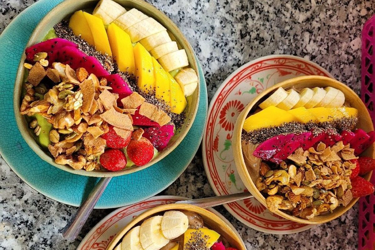 A colorful healthy smoothie bowl topped with fresh tropical fruits and granola
