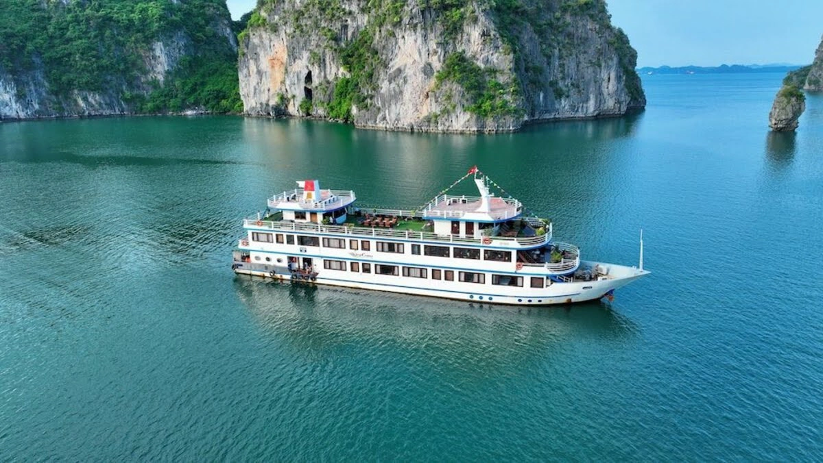 Multi-deck cruise ship anchored between towering limestone cliffs 