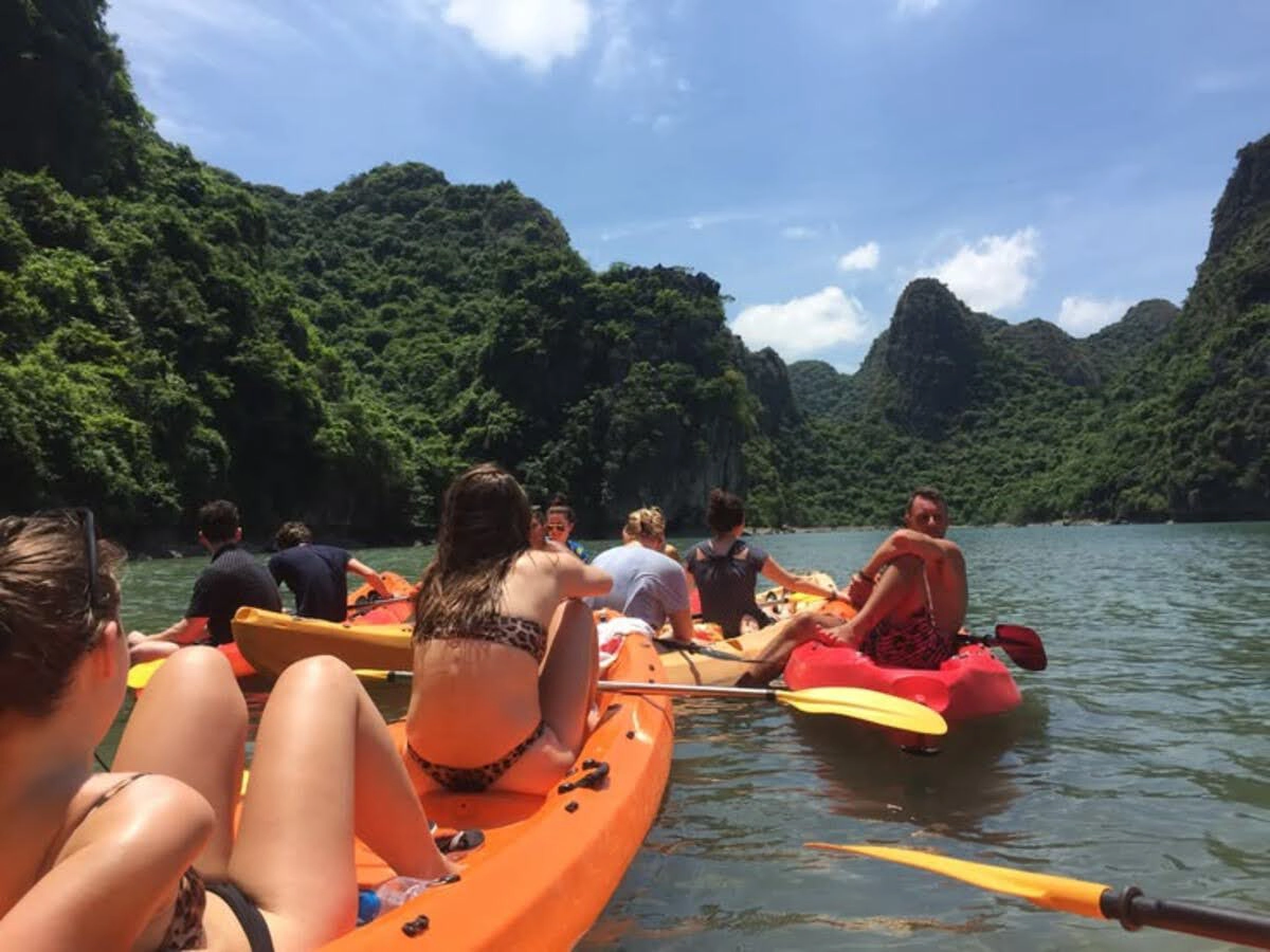 Tourists kayaking in a crowded group among limestone cliffs