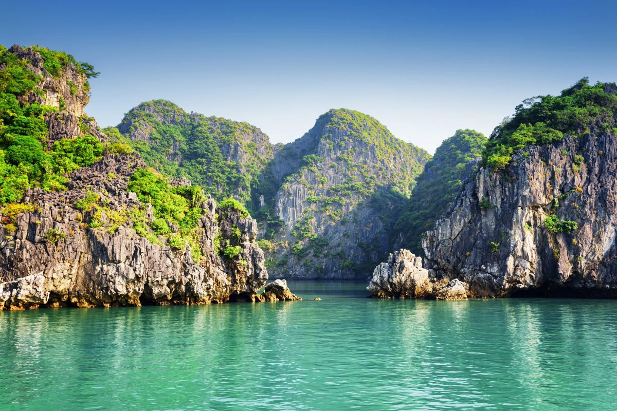 Misty limestone karsts rising from the calm winter waters of the bay