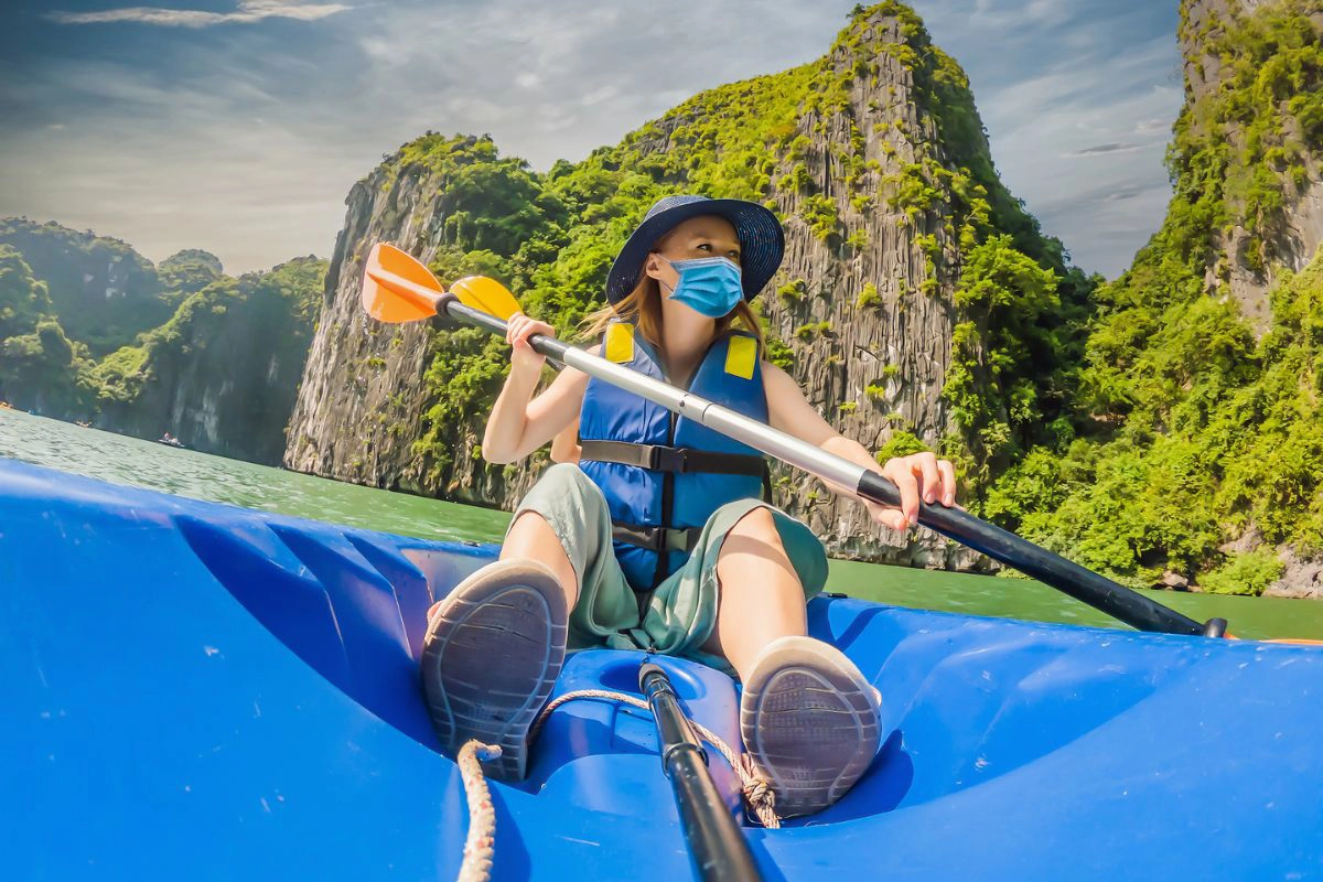 Travelers wearing light jackets while kayaking near towering limestone cliffs