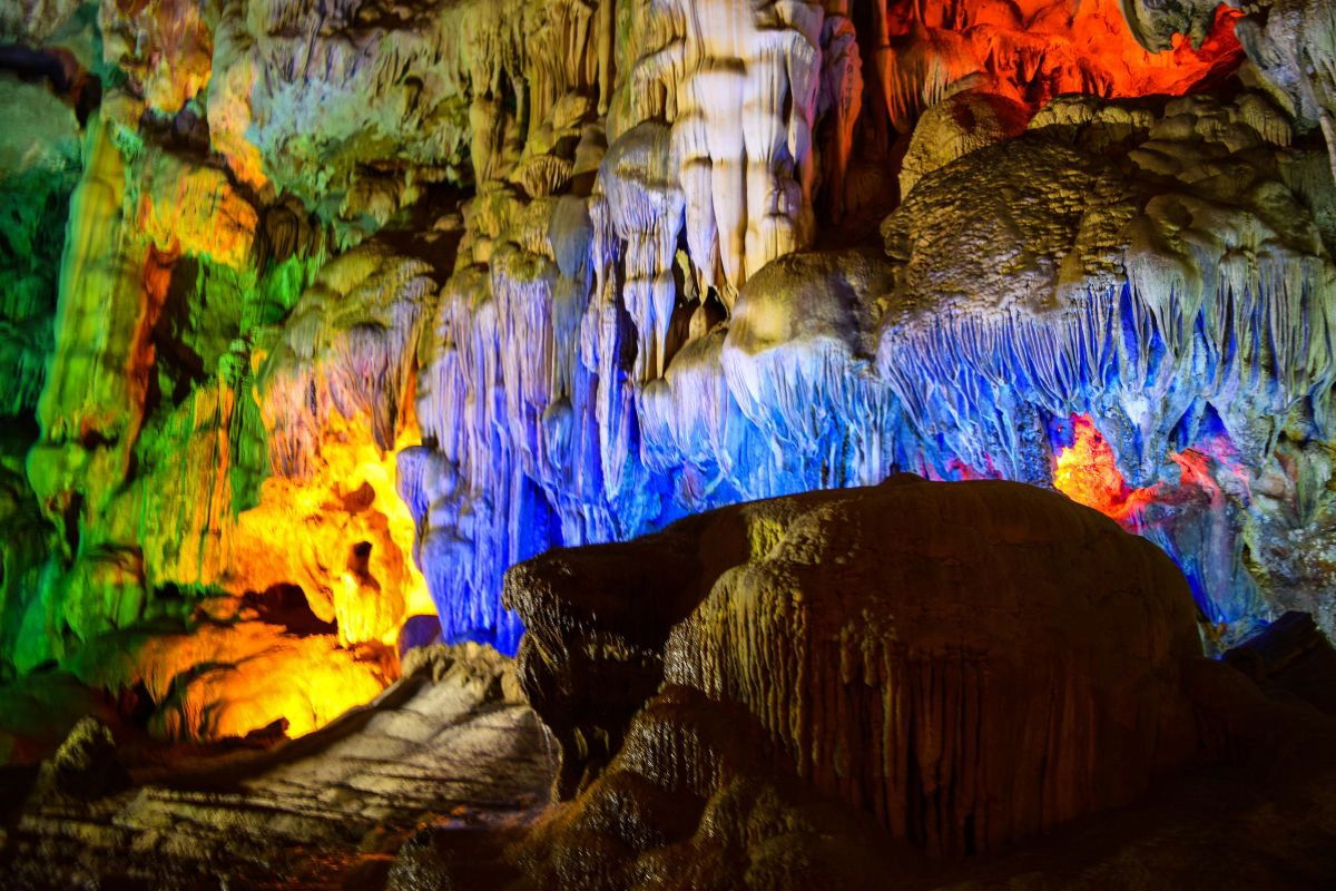 Visitors walking up the stone steps inside a beautifully lit cavern