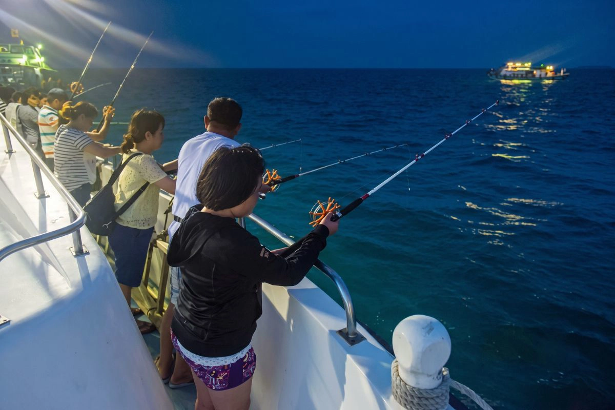 Passenger moving a fishing rod under the bright deck lights