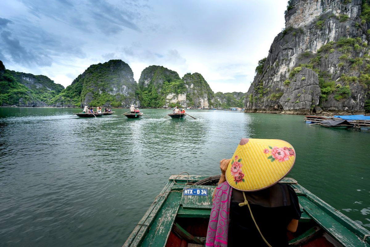 Traditional wooden boat sailing past famous limestone karsts